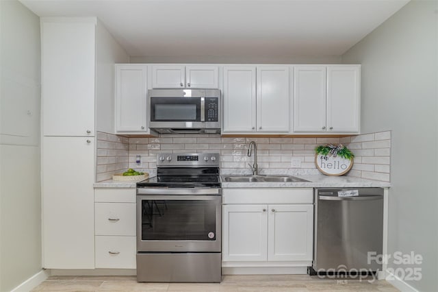 kitchen featuring appliances with stainless steel finishes, light countertops, a sink, and backsplash