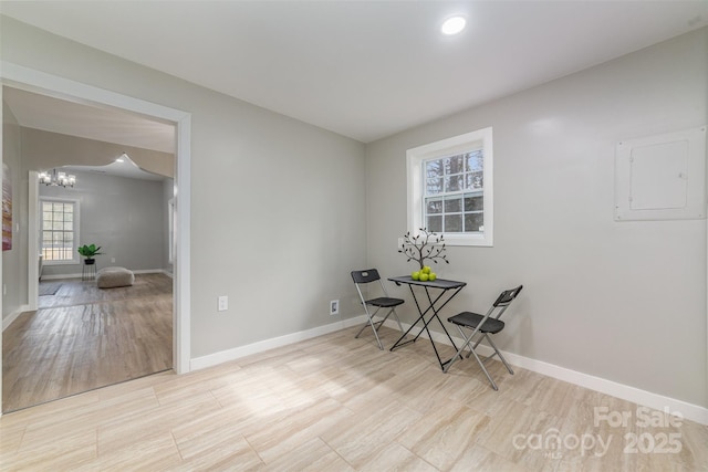 dining room with a notable chandelier, wood finished floors, electric panel, and baseboards