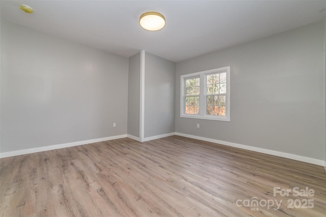 spare room with baseboards and wood finished floors