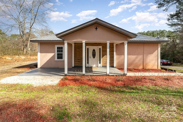 view of front facade with metal roof, a porch, and stucco siding