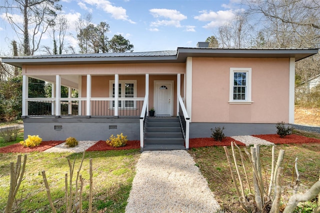 view of front facade with covered porch, metal roof, crawl space, and stucco siding