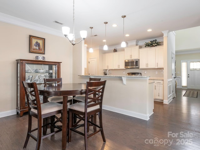 dining space featuring a notable chandelier, dark wood-style flooring, visible vents, baseboards, and ornamental molding