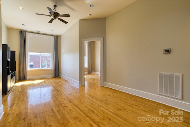 unfurnished living room with visible vents, baseboards, vaulted ceiling, light wood-style flooring, and a ceiling fan