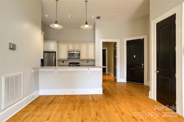 kitchen with a kitchen bar, visible vents, appliances with stainless steel finishes, and light countertops