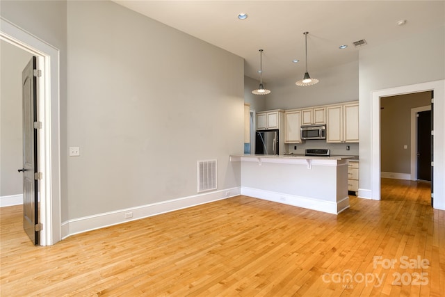 kitchen featuring a peninsula, light wood-style floors, visible vents, and appliances with stainless steel finishes