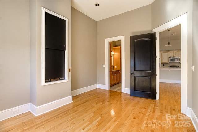 empty room with baseboards and light wood-type flooring