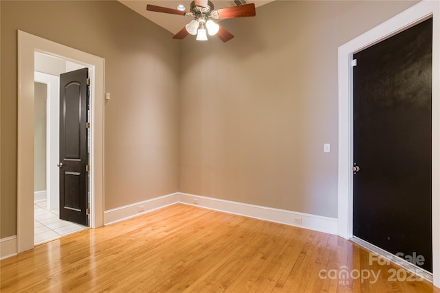 spare room with baseboards, light wood-style flooring, and a ceiling fan