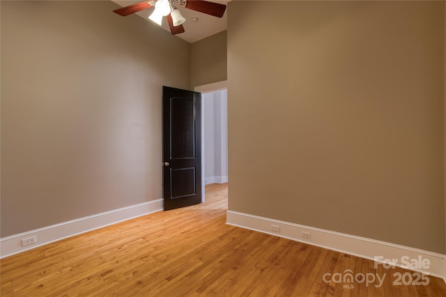 empty room featuring a ceiling fan, baseboards, and light wood-type flooring