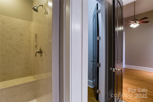 bathroom with tiled shower, ceiling fan, and wood finished floors