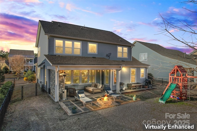 rear view of property featuring a playground, a fenced backyard, roof with shingles, a patio area, and an outdoor living space with a fire pit