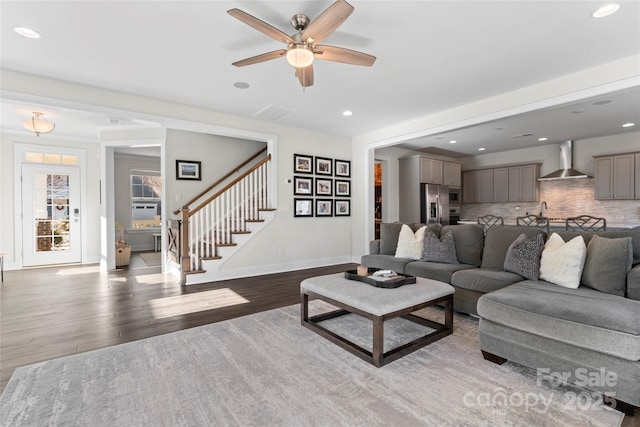 living area featuring recessed lighting, wood finished floors, visible vents, baseboards, and stairway