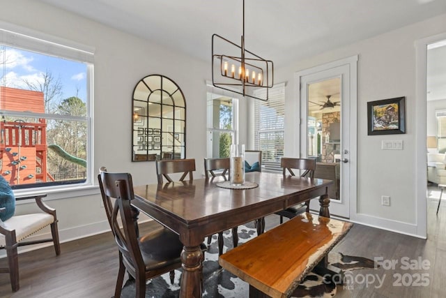 dining space with dark wood-style floors, a chandelier, and baseboards