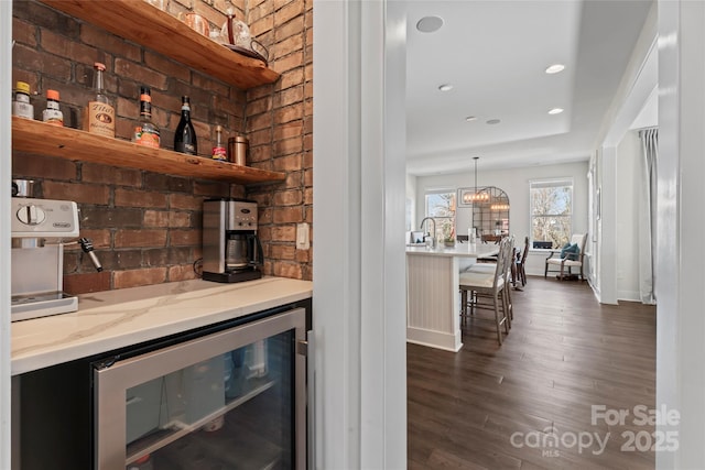 bar featuring recessed lighting, beverage cooler, a bar, dark wood finished floors, and pendant lighting