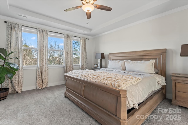 bedroom with baseboards, a raised ceiling, visible vents, and light colored carpet