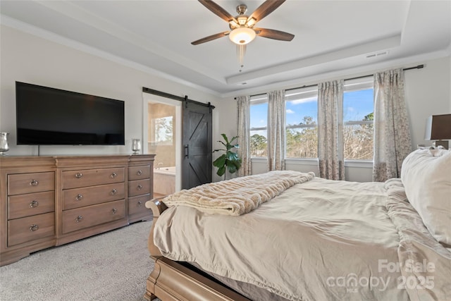 bedroom with a barn door, a raised ceiling, connected bathroom, and light colored carpet