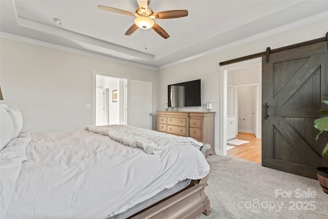 bedroom with a barn door, light colored carpet, a ceiling fan, ornamental molding, and a raised ceiling