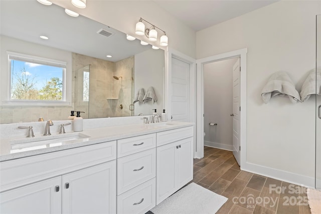 full bathroom featuring wood finish floors, visible vents, a sink, and a shower stall