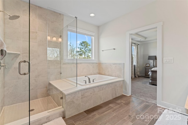 ensuite bathroom featuring baseboards, connected bathroom, wood finish floors, a shower stall, and a bath
