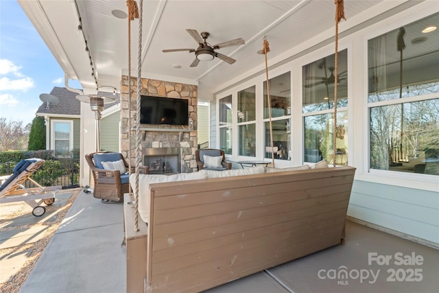 view of patio with an outdoor living space with a fireplace and a ceiling fan