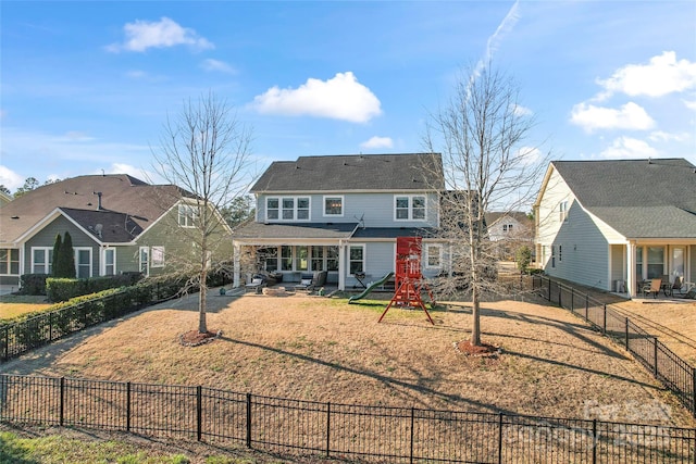 rear view of property featuring a patio, a playground, a fenced backyard, a yard, and driveway