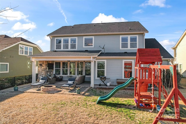 back of house with a playground, a fire pit, fence, a yard, and a patio area