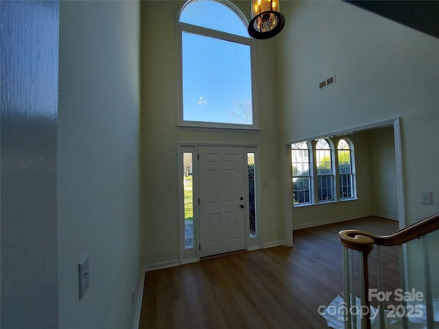 foyer featuring plenty of natural light, wood finished floors, visible vents, and a towering ceiling