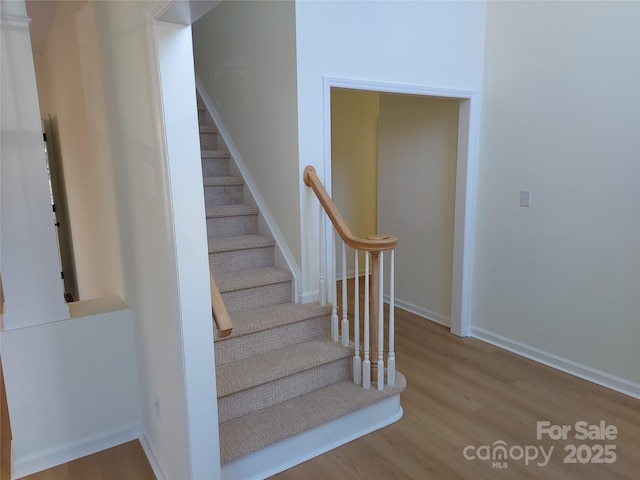 staircase with baseboards and wood finished floors