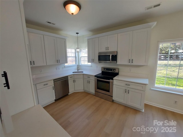 kitchen featuring visible vents, white cabinets, stainless steel appliances, and a sink