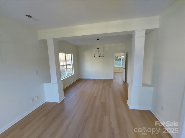 unfurnished dining area with visible vents, baseboards, light wood-type flooring, and ornate columns