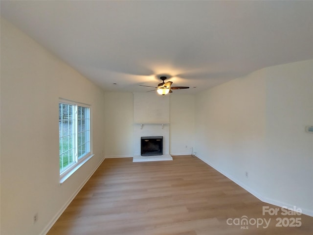 unfurnished living room featuring a brick fireplace, light wood-style flooring, and a ceiling fan