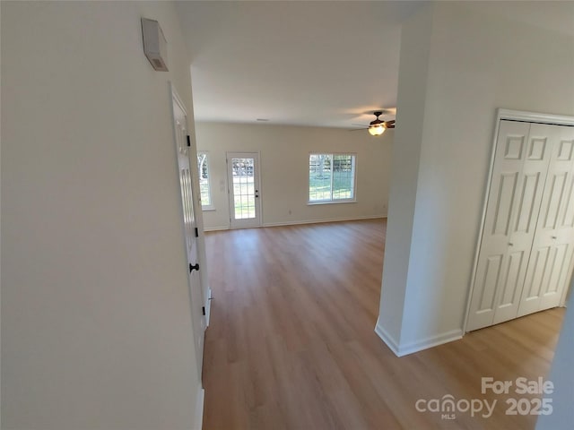 hall featuring baseboards and light wood finished floors