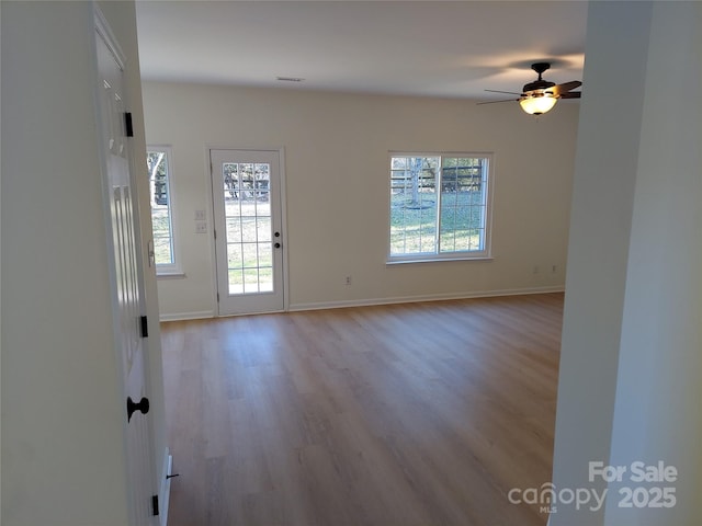 empty room with visible vents, ceiling fan, baseboards, and light wood-style floors