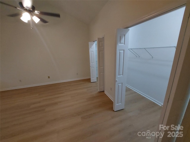 unfurnished bedroom featuring lofted ceiling, light wood-style flooring, baseboards, and ceiling fan