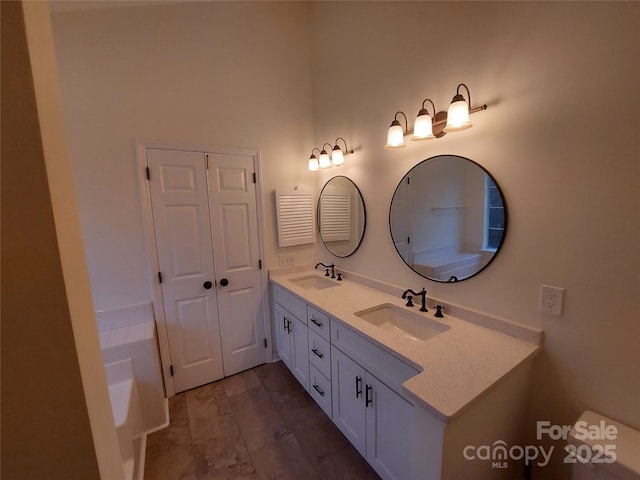 full bathroom featuring double vanity, a bathtub, and a sink