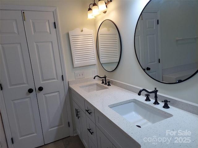 full bathroom with double vanity, a closet, and a sink