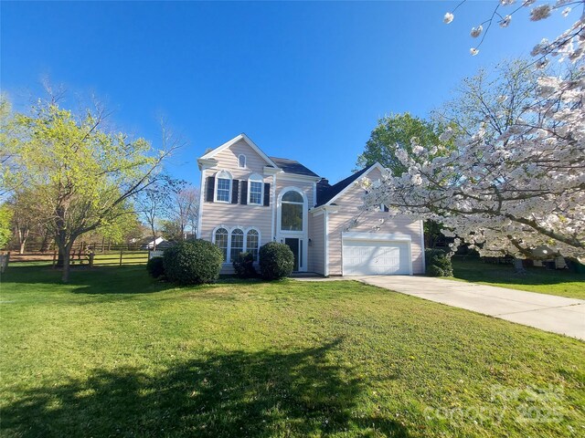 traditional-style home featuring a front yard, concrete driveway, fence, and an attached garage