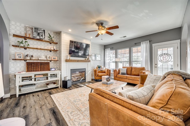 living room with wallpapered walls, visible vents, wood finished floors, a fireplace, and recessed lighting