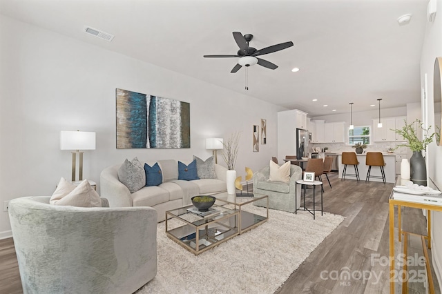 living room featuring a ceiling fan, recessed lighting, visible vents, and wood finished floors