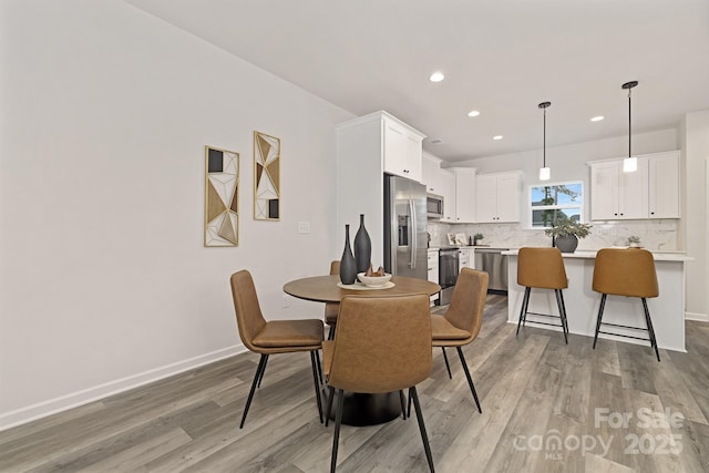 dining space with light wood-style floors, baseboards, and recessed lighting