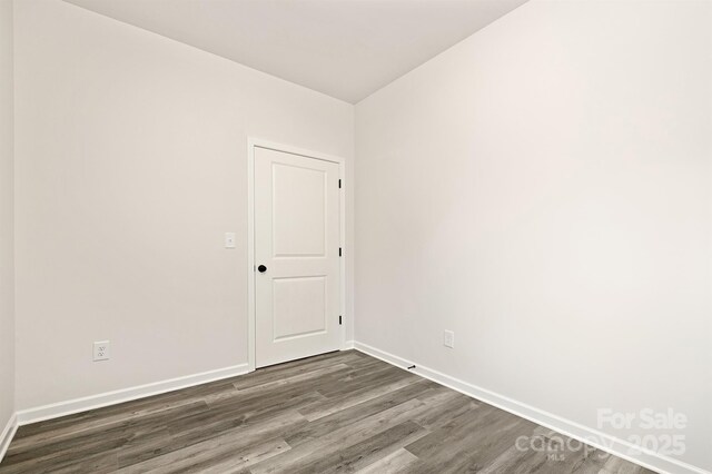 unfurnished room with dark wood finished floors and baseboards