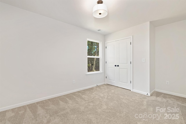 unfurnished bedroom featuring a closet, light colored carpet, visible vents, and baseboards