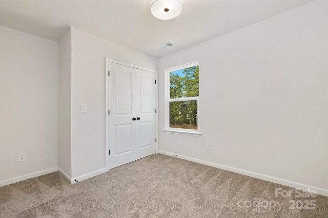 unfurnished bedroom featuring light colored carpet, visible vents, and baseboards