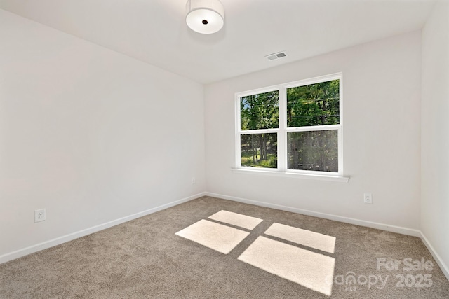 unfurnished room featuring carpet floors, visible vents, and baseboards