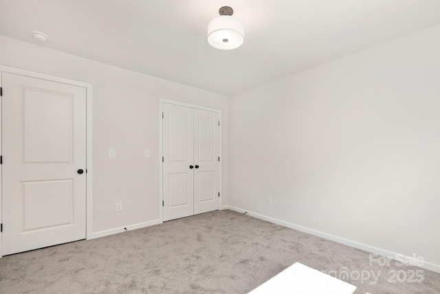 unfurnished bedroom featuring baseboards, a closet, and light colored carpet