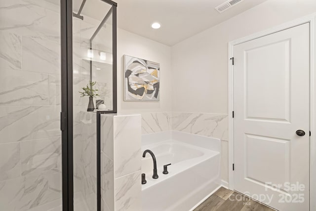 full bathroom with wood finished floors, a garden tub, visible vents, and a shower stall