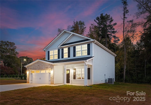 traditional-style house featuring an attached garage, a front lawn, central AC, and concrete driveway