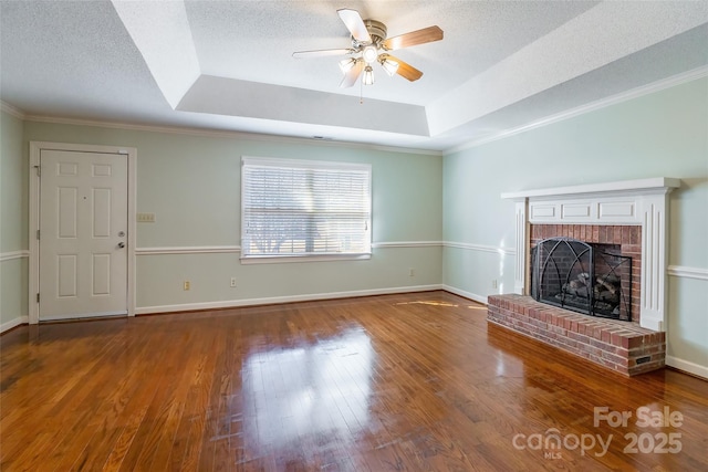 unfurnished living room with a textured ceiling, hardwood / wood-style floors, a raised ceiling, and a brick fireplace