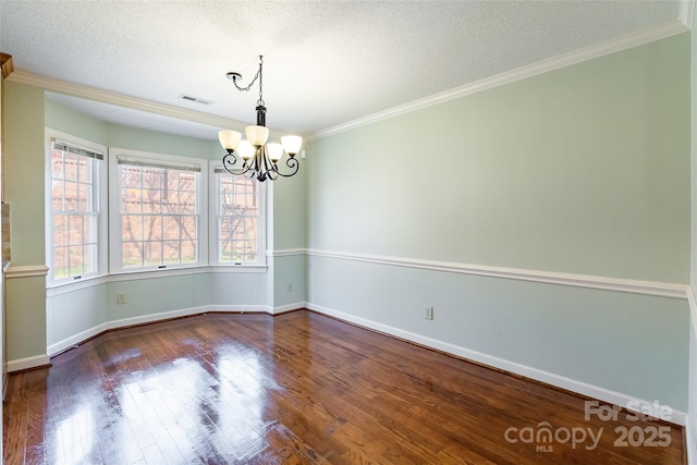 spare room with ornamental molding, a textured ceiling, an inviting chandelier, and dark hardwood / wood-style floors