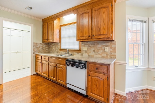 kitchen featuring white dishwasher, wood-type flooring, backsplash, and sink