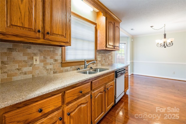 kitchen featuring white dishwasher, decorative light fixtures, ornamental molding, and sink